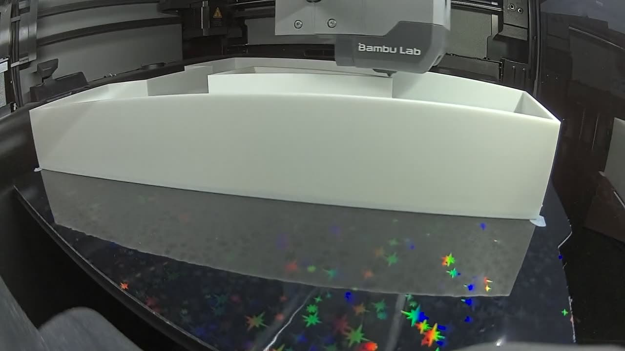 Literă volumetrică albă în timpul printării pe o imprimantă 3D Bambu Lab din atelier